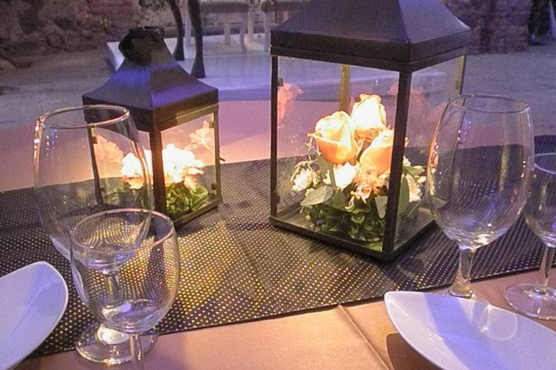 Linternas de herrería con flores y vela sobre la mesa