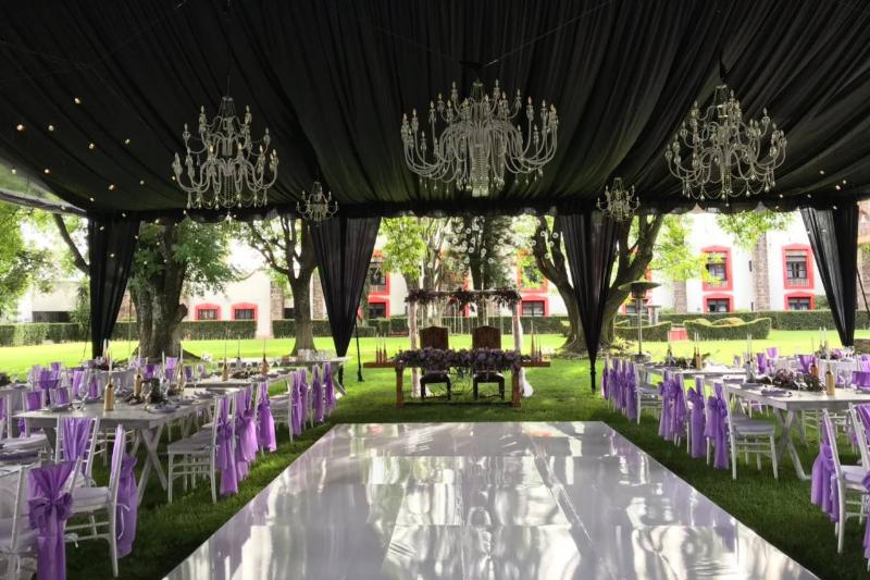 Candiles de cristal y telas negras en una carpa de jardín