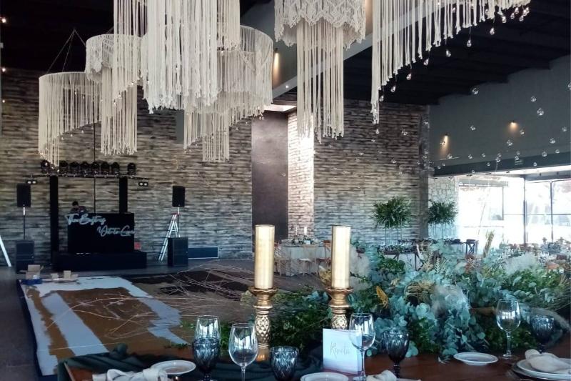 Lámparas de macramé y velas altas en candelabros dorados