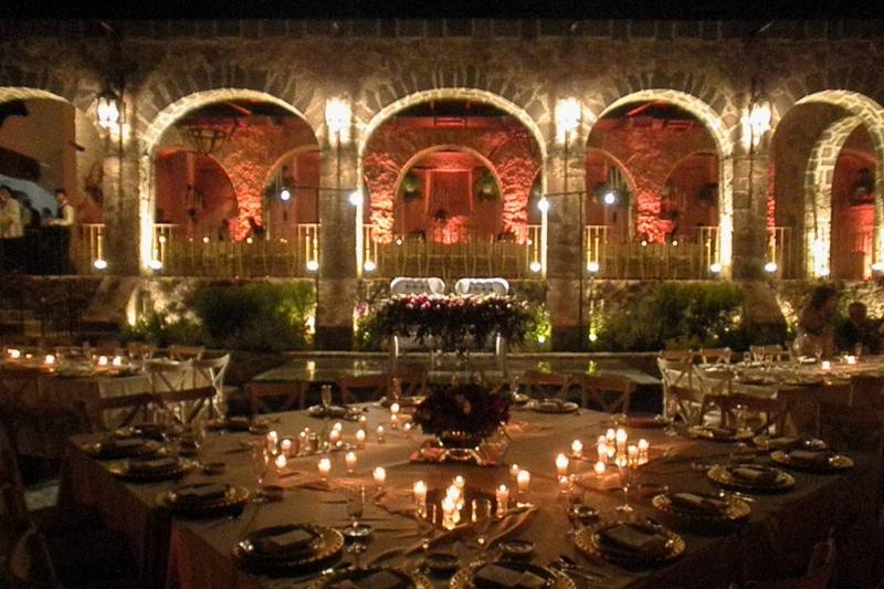 Arcos iluminados en ámbar y velas sobre cada mesa